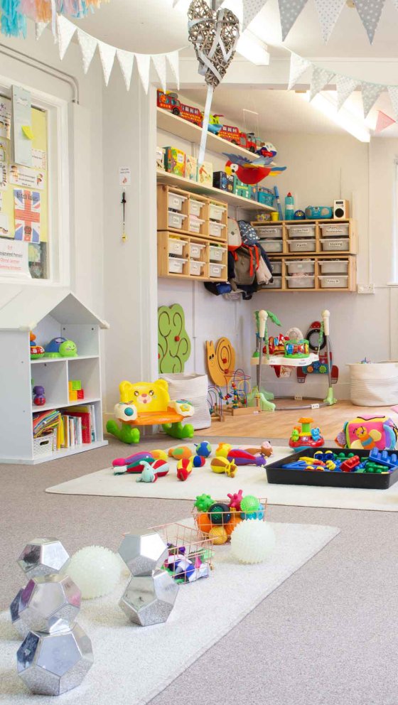 Een kinderbedje verlicht door de verscheidenheid aan kleuren van het speelgoed dat overal verspreid ligt.