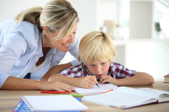 Een professionele nanny helpt een jongen met zijn huiswerk na school.